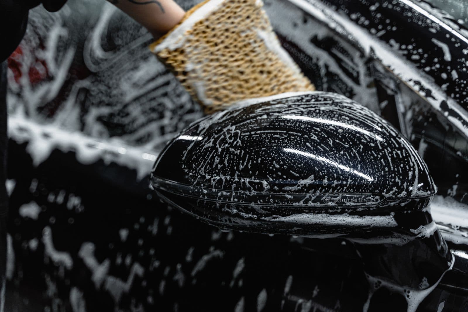 Wash mitt working thick foam over a black mirror during a hand wash