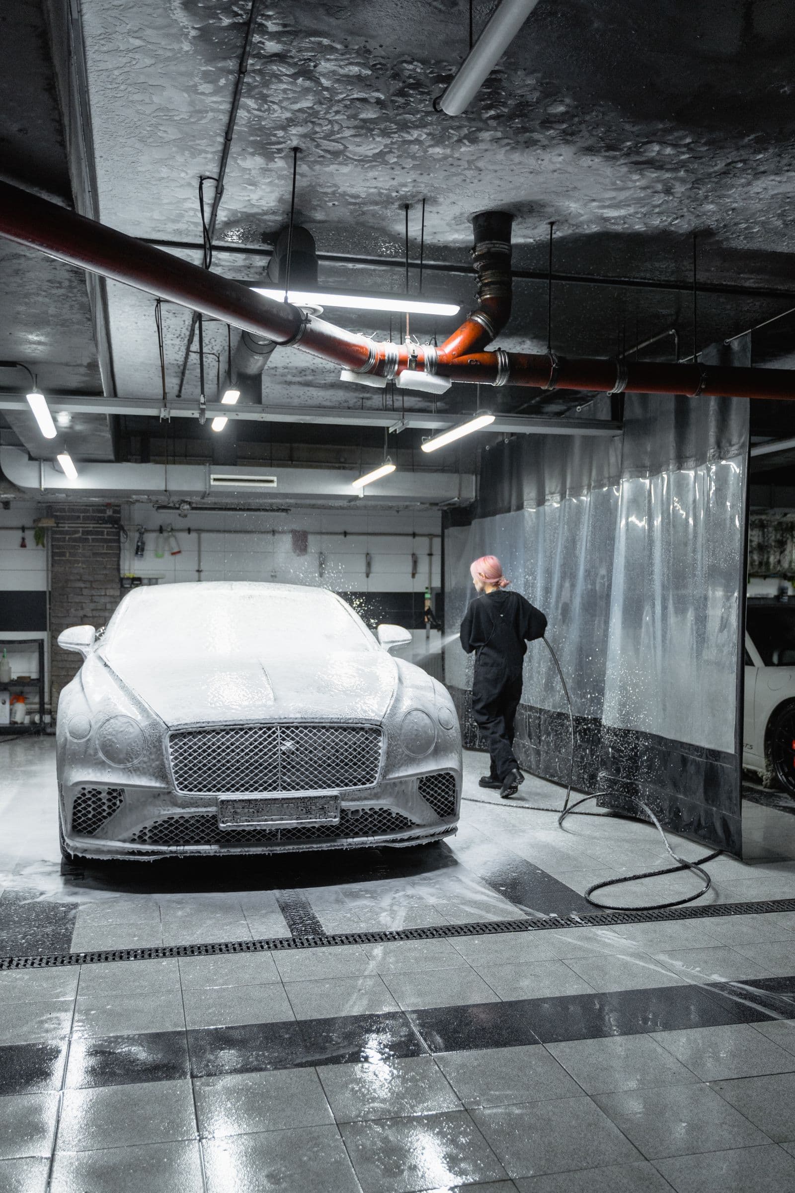 Coupe covered in thick white snow foam during an exterior detail