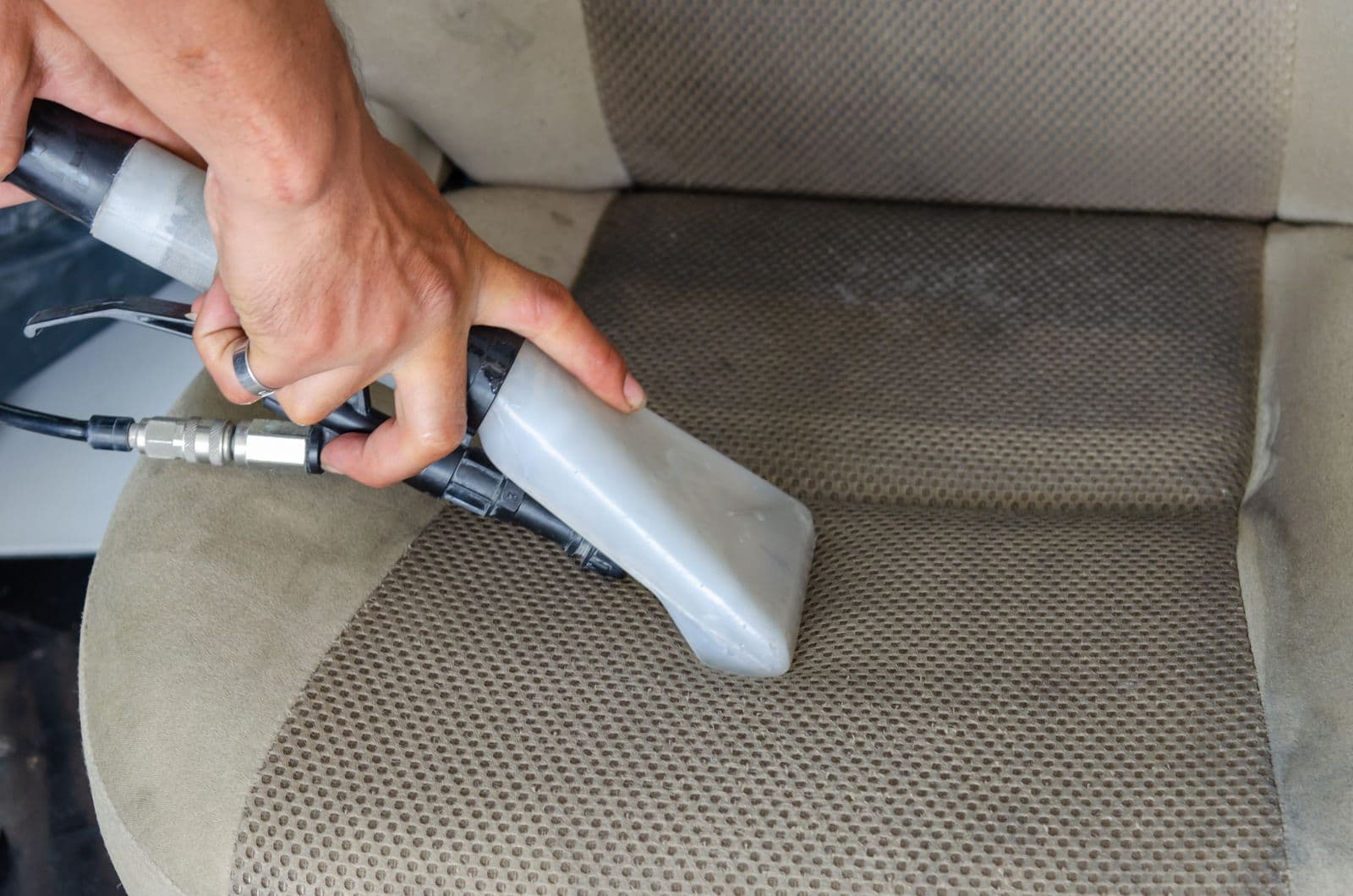 Extractor pulling dirt out of a fabric car seat during an interior detail
